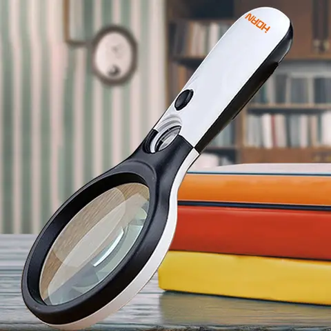 Loupe à main éclairée 3 LED posée sur un texte imprimé, grossissement élevé